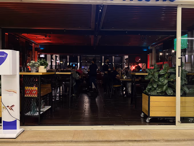 Evening view into Crepaway Sulaymaniyah — dark wood-look floor tiles running from the open terrace into the red-lit dining room.