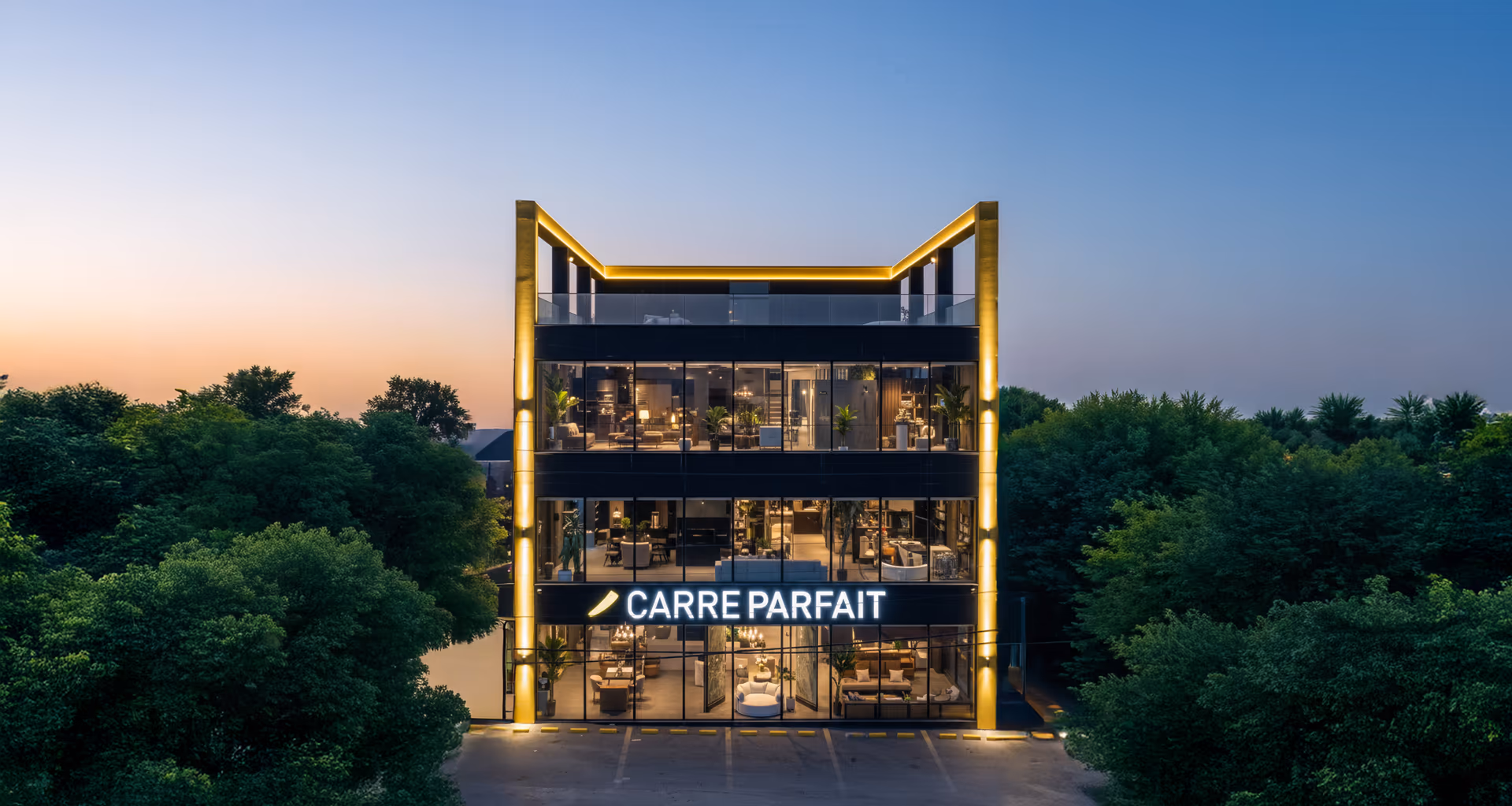 Carré Parfait storefront at dusk — a four-storey glass building with a yellow LED frame and the illuminated wordmark on the second floor, set against trees and a soft sunset sky.