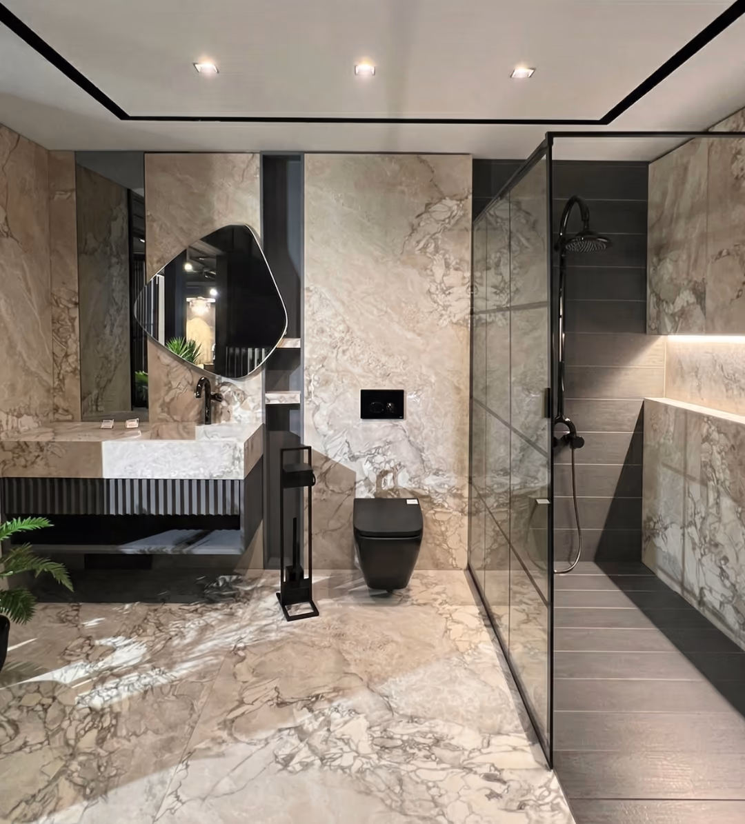 Bathroom in cream marble-look porcelain with a floating stone vanity and basin, a black wall-hung WC and a glass shower screen.