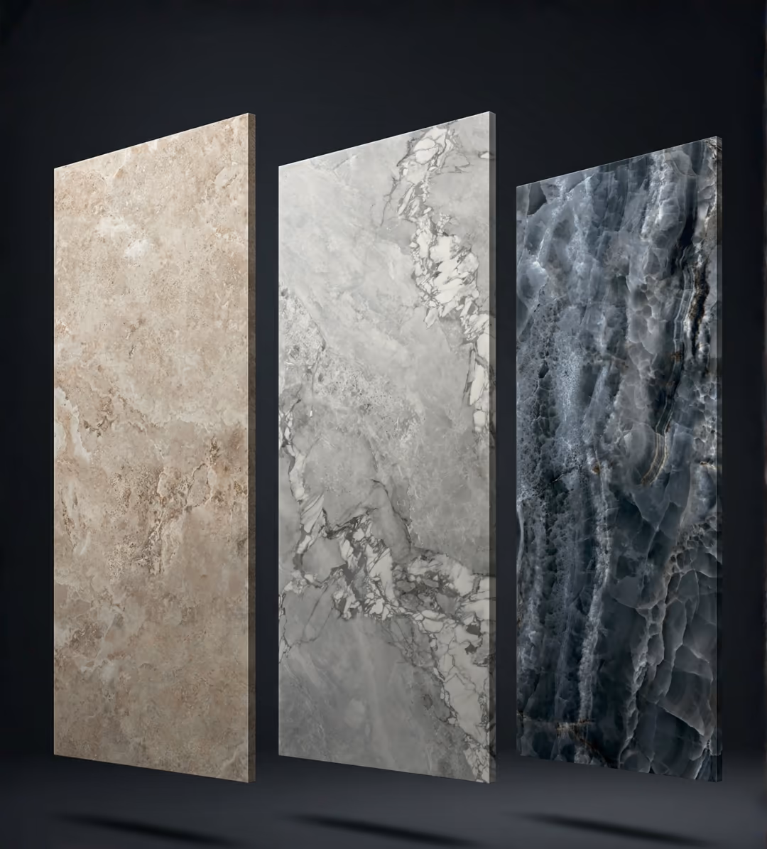 Three porcelain slabs standing upright on a dark floor: beige travertine-look, grey Calacatta-look and dark grey onyx-look.